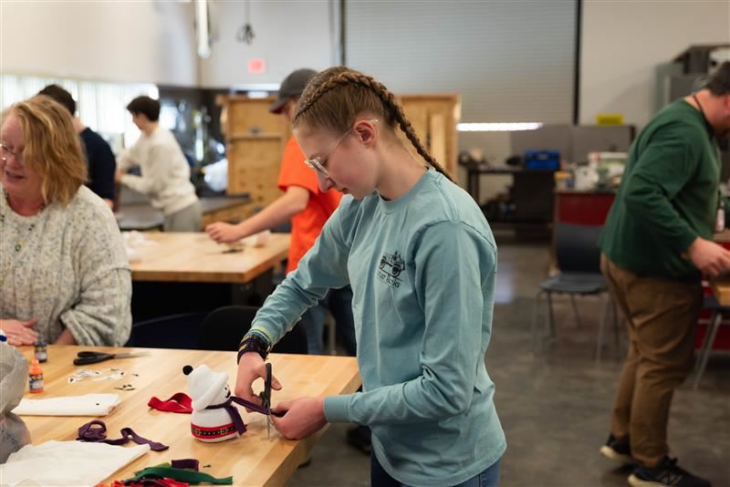  A P-TECH student adds the finishing touches to a sock snowman in her manufacturing station